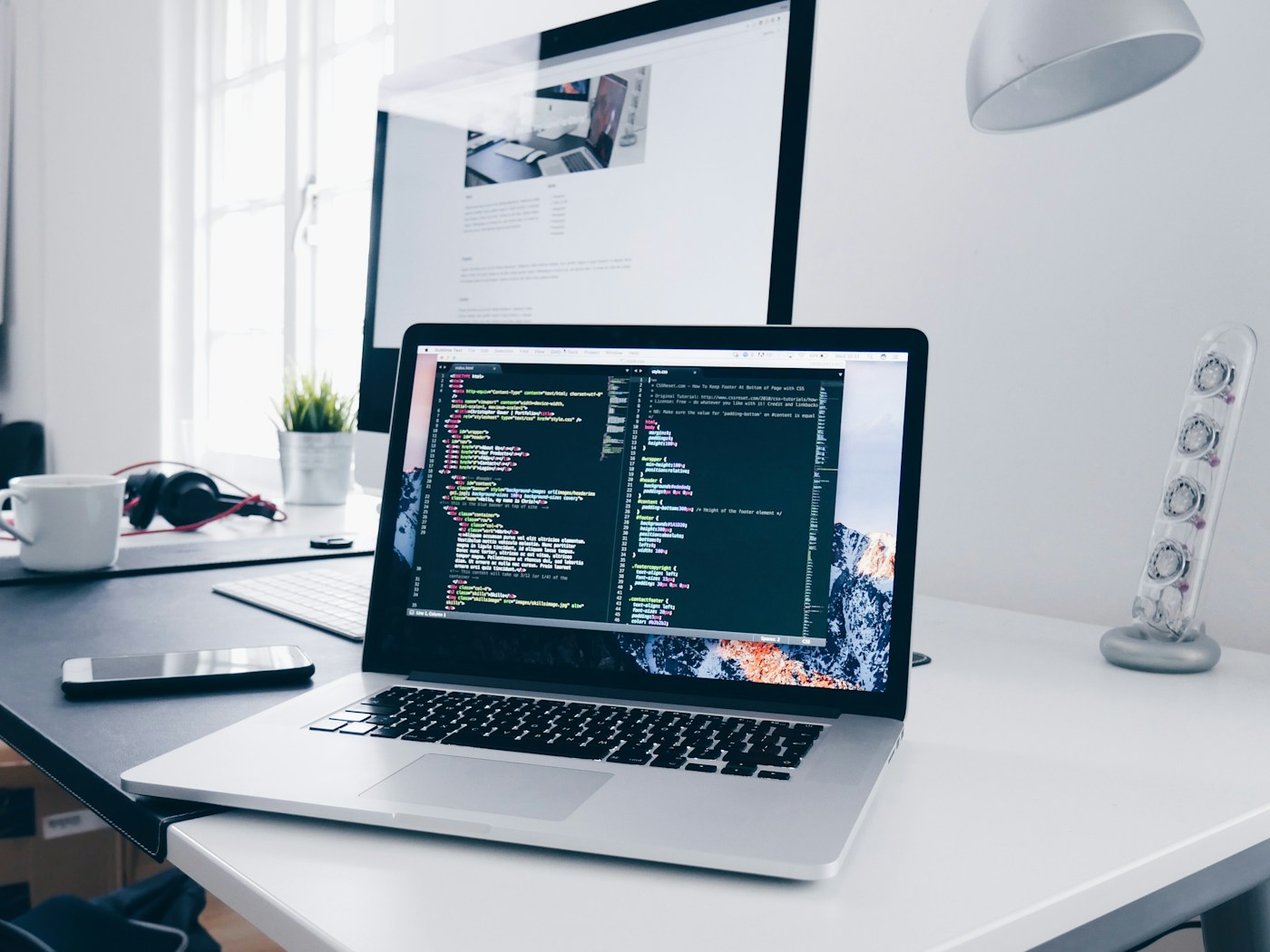 MacBook con schermata di sviluppo e layout di landing page